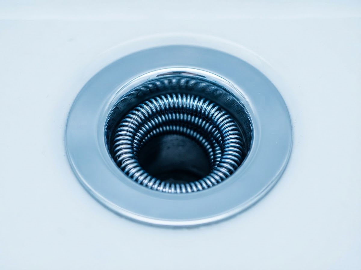Professional drain snake cable inside a chrome drain opening